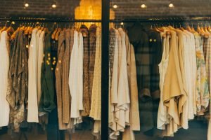 A rail of beige clothes behind a glass shop window