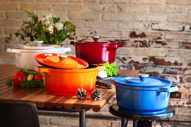 3 slow cooker dishes in orange red and blue. In front of a brick wall.