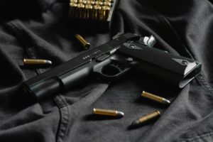 black handgun on black cloth with bullets