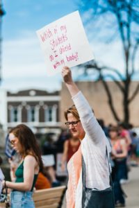 Teacher holding sign at the March for Our Lives rally in Texas 2018. The sign reads: Which of my students do I shield with my body?