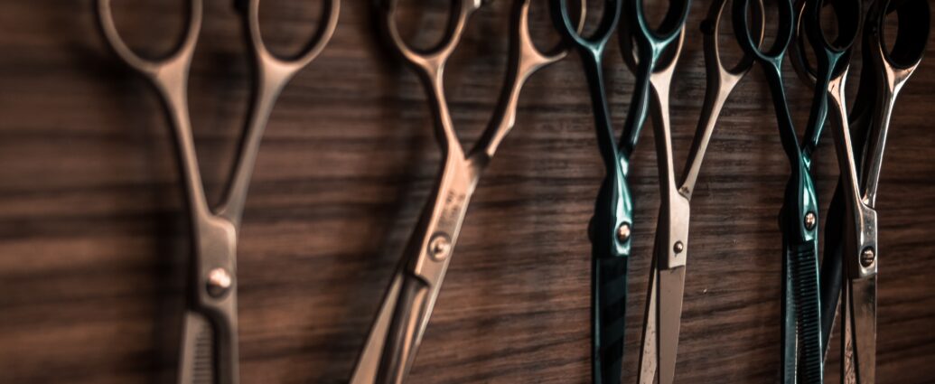 Row of hairdressing scissors hanging on a wooden wall