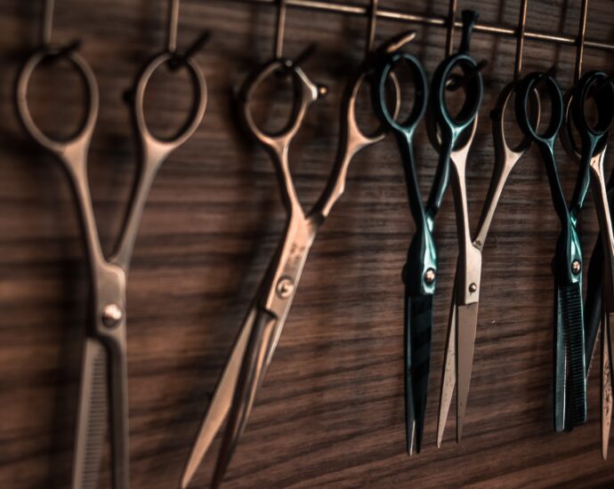 Row of hairdressing scissors hanging on a wooden wall