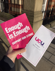 A hand holds a bright pink flyer reading "Enough is Enough" and a white leaflet cont