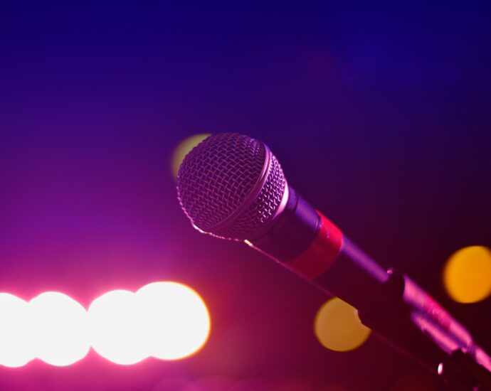 A microphone set up on stage ready for a performance, with purple lights in the distance.