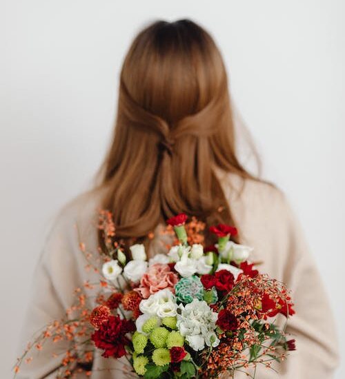 Red headed woman with her back to the camera, holding a bouquet of flowers behind her. She likens the main character of It Ends With Us.