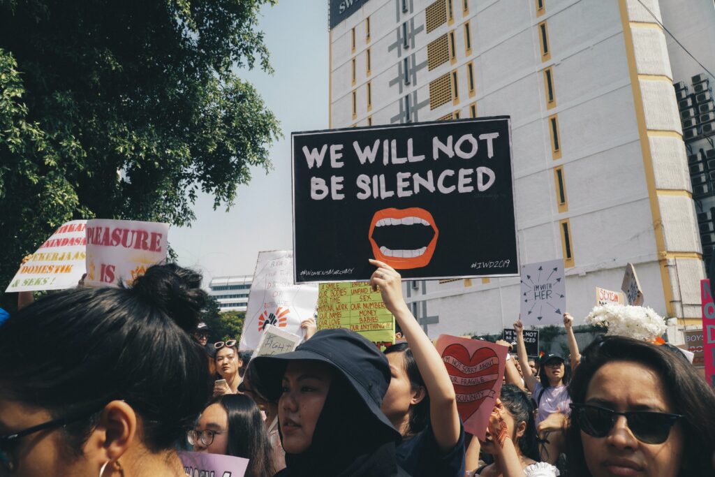 Image of a somebody holding up a sign at a women's rights protest saying "we will not be silenced"