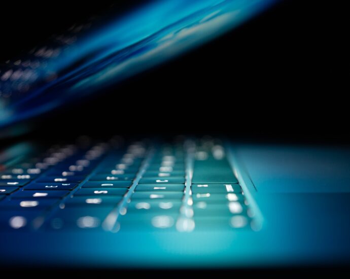 Side view of a laptop folded almost completely down. The room is dark so the only light is a blue-green glow from the screen. It sets the sinister tone of the story about Stephen Bear's crimes.