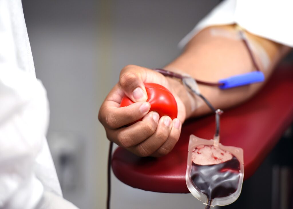 A blood donor squeezes a ball while giving blood.