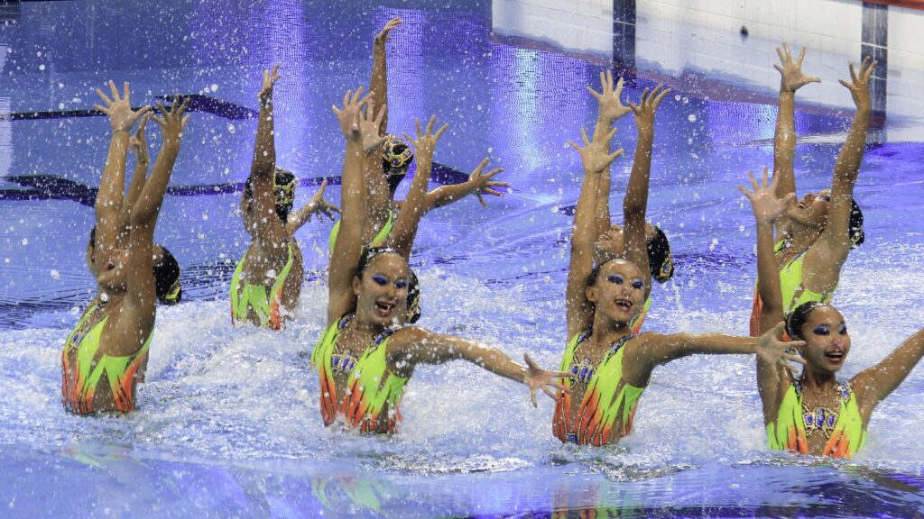 a team of young women completing an artistic swimming performance