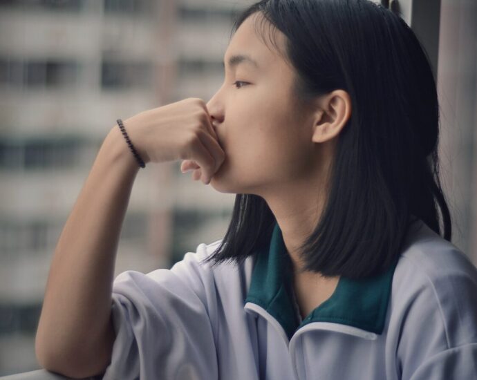 girl leaning on hand, staring out of window and overthinking