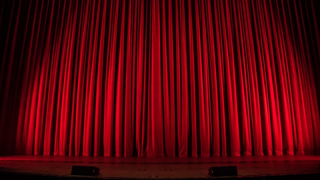 Theatre stage with red curtain drawn,