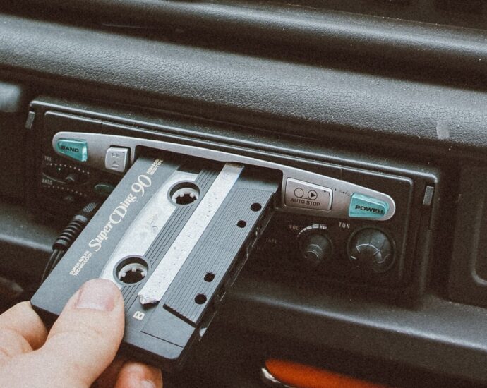 A vintage style shot of somebody inserting a cassette into the cassette player of their car.