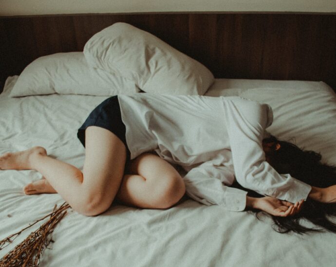 Woman lying on a bed, in distress.