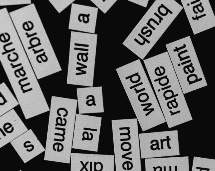 Image shows a black background with white stickers containing words in different languages