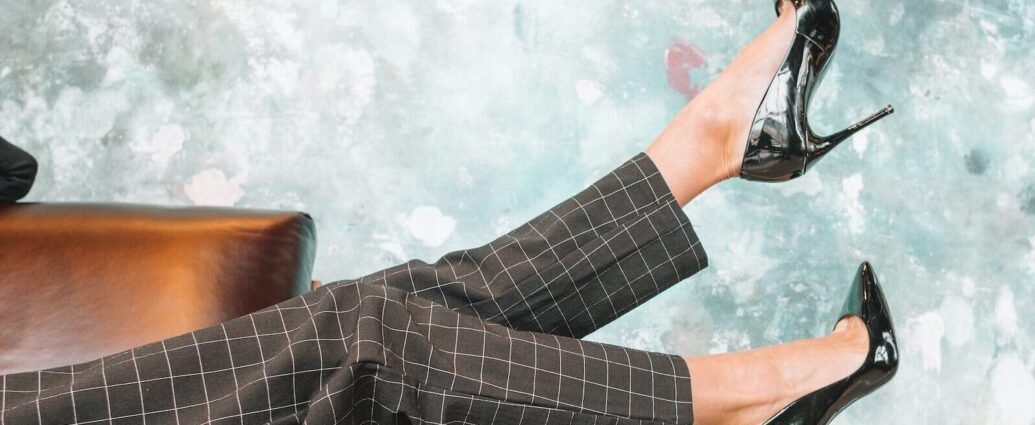 A pair of legs wearing fashionable trousers and fancy high heel shoes.