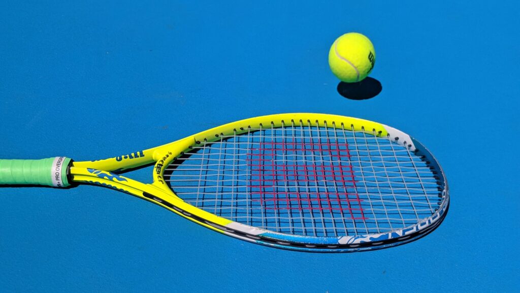 Tennis racket and ball on blue court
