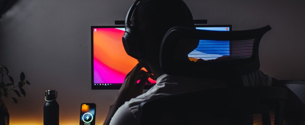 Person wears headphones in front of computer. There is a clapperboard pictured left, a common tool for YouTubers like Ballinger
