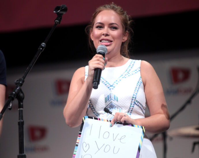 Tanya Burr speaking at the 2014 VidCon. She holds a sign that reads 'I love you Burr bears'.