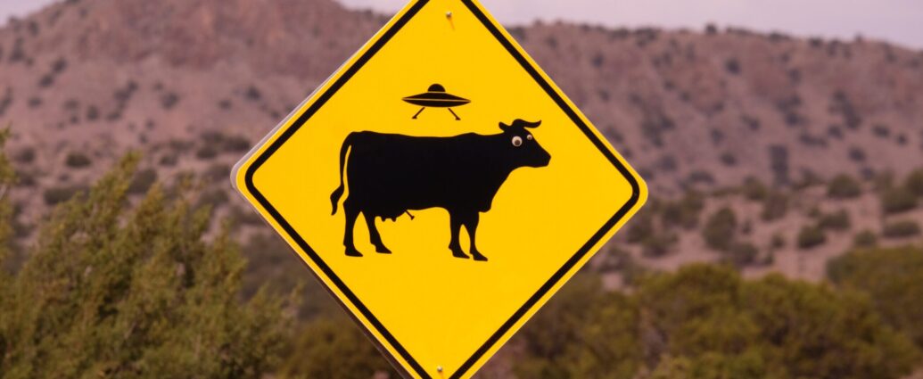Road sign depicting a UFO abducting a cow.