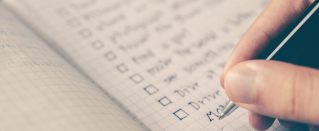 Image shows a person writing a daily habits to-do list in a notepad