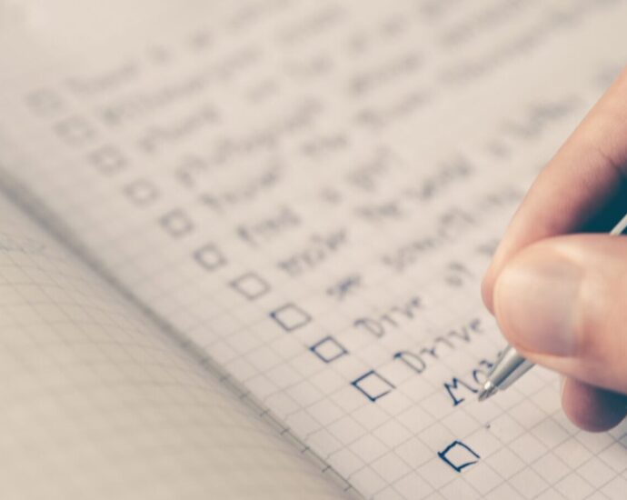 Image shows a person writing a daily habits to-do list in a notepad