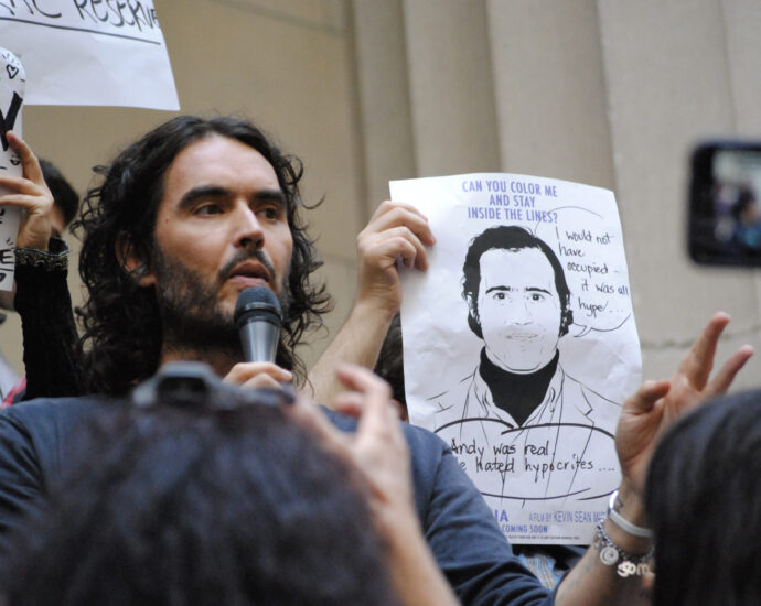 Image shows Russell Brand speaking at a protest on Wall Street, NYC.