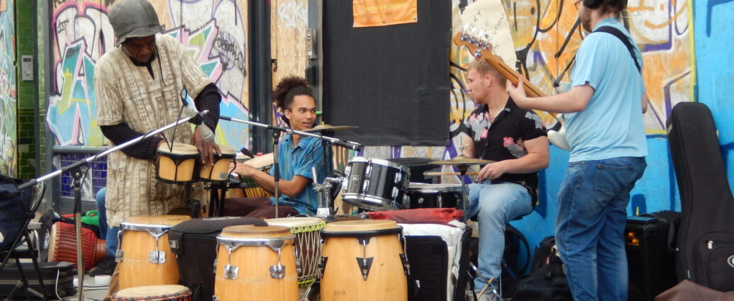 Four musicians surrounded by drums in preparation for a performance at Notting Hill Carnival.