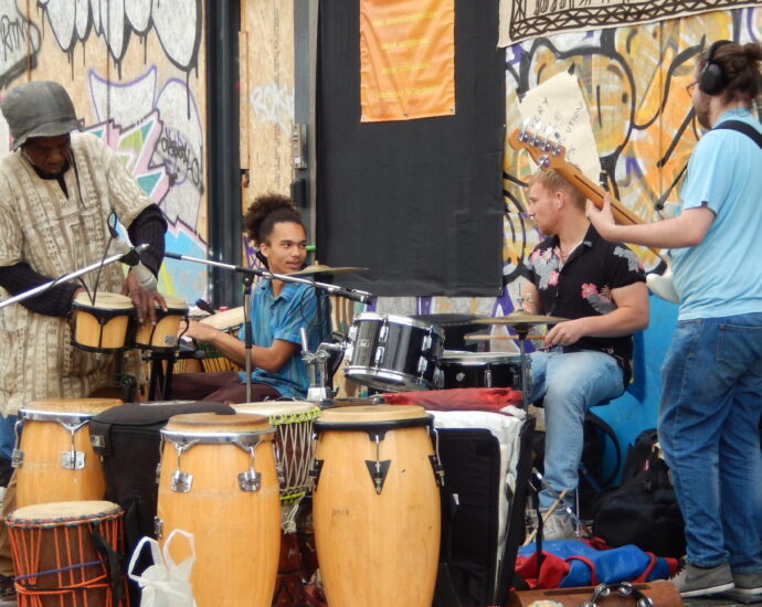 Four musicians surrounded by drums in preparation for a performance at Notting Hill Carnival.