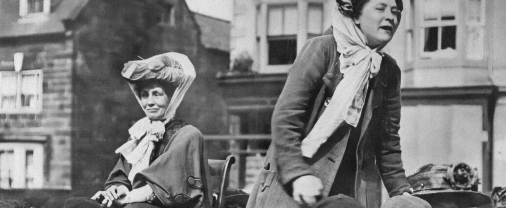 Two suffragettes standing on a cart, bringing their message. England, location unknown, about 1900.