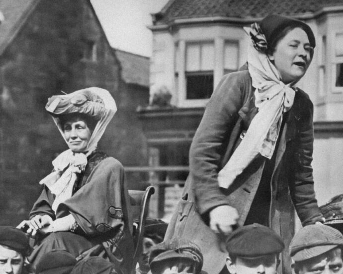Two suffragettes standing on a cart, bringing their message. England, location unknown, about 1900.