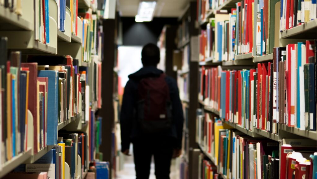 A student standing in the aisles of a library.