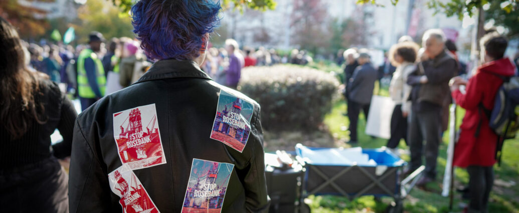 An activist with "Stop Rosebank" leaflets attached to the front and back of her jacket.