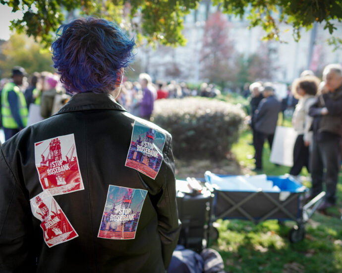 An activist with "Stop Rosebank" leaflets attached to the front and back of her jacket.