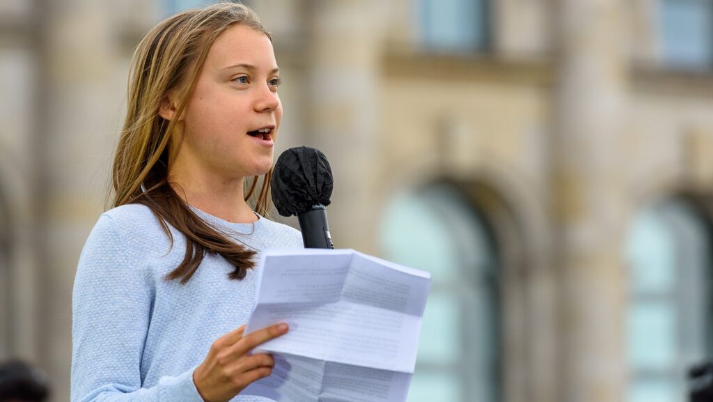 Image shows Greta Thunberg reading speech.