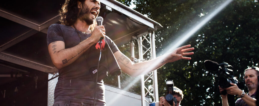 An image of Russell Brand speaking at an event.