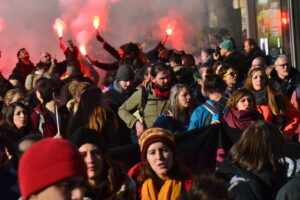 A crowd of protestors hold red smoke flares, amidst protests opposing Macron's controversial pension reform plans, in Paris.