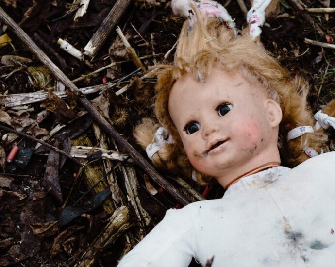 Image shows a tarnished Baby Annabel doll lying in the dirst.