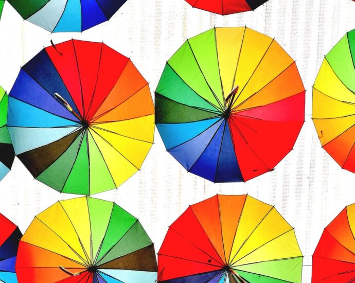 Image shows various umbrellas of different colors hanging horizontally