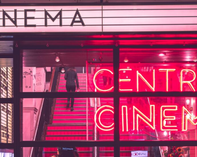 The exterior of a retro-style cinema with neon pink signs.