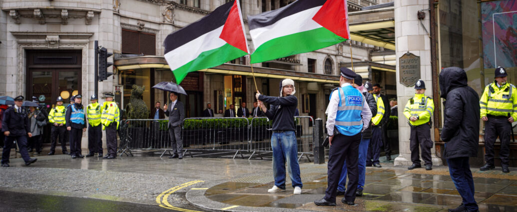 Two activists raise Palestinian flags in front of London's Savoy Hotel.
