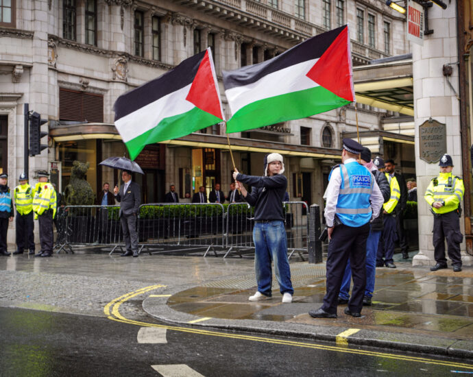 Two activists raise Palestinian flags in front of London's Savoy Hotel.