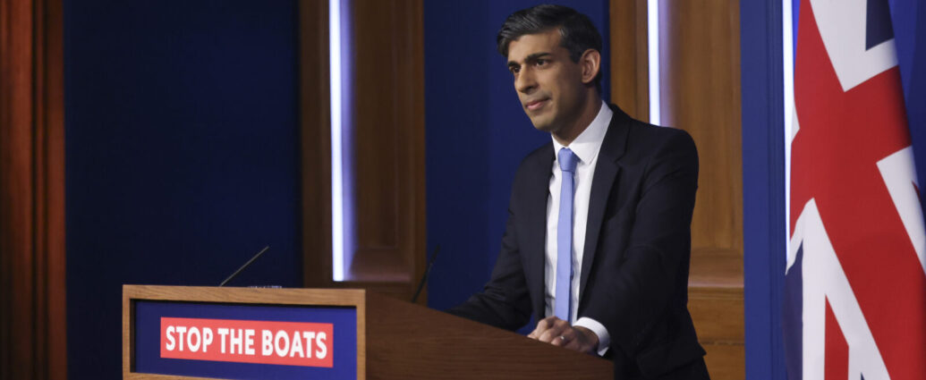 UK Prime Minister Rishi Sunak behind a podium that says 'stop the boats'