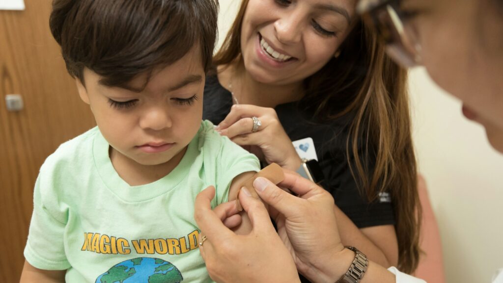Image shows young boy receiving a vaccination in his arm.