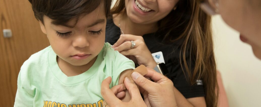 Image shows young boy receiving a vaccination in his arm.