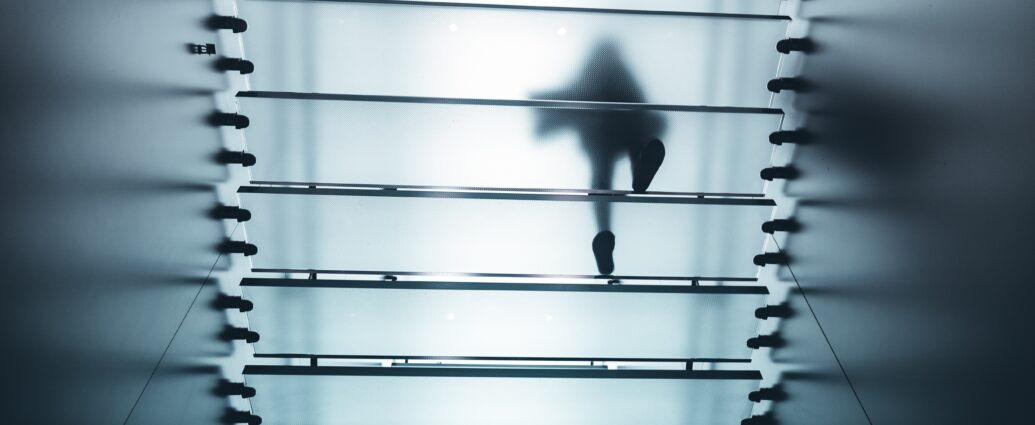 A figure walking above frosted glass stairs