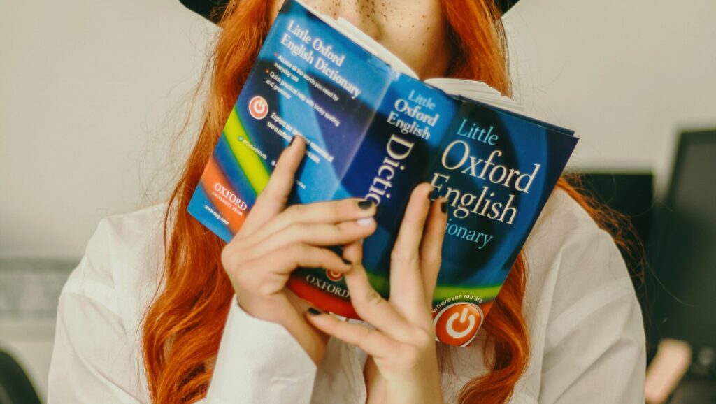 A woman holds an Oxford English Dictionary.