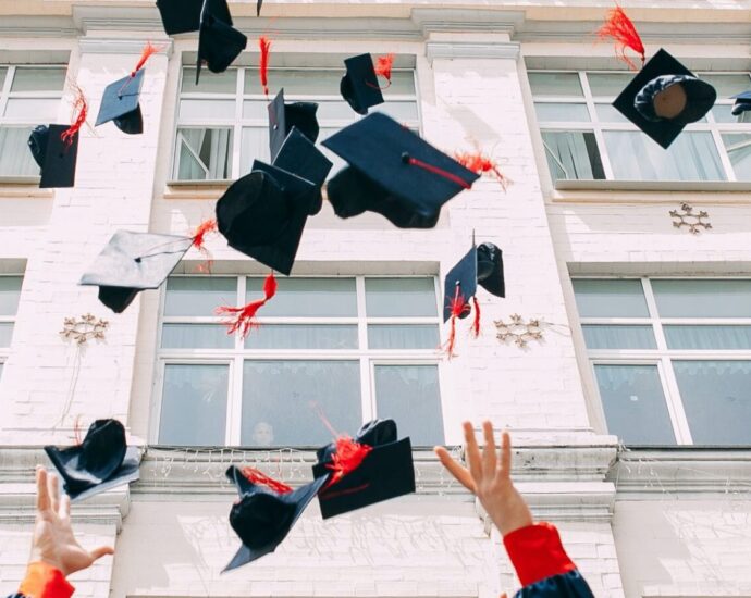 Image shows a group of graduates throwing their caps into the air [after graduating]