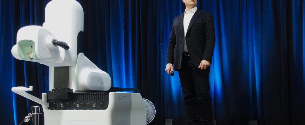 Elon Musk stands next to Neuralink robot device