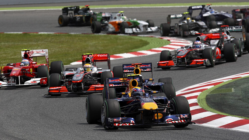 Image shows formula 1 cars on a track.