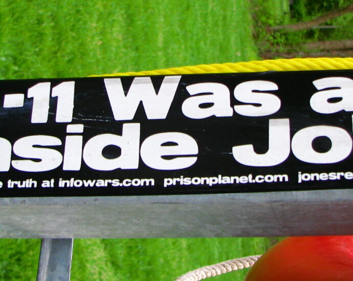 Image shows a sticker that reads '9/11 was an inside job' [conspiracy theories]